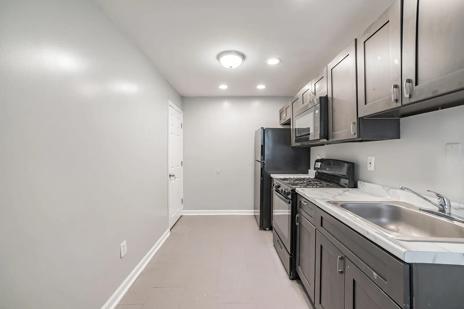 Gray galley kitchen with white counters and stainless appliances