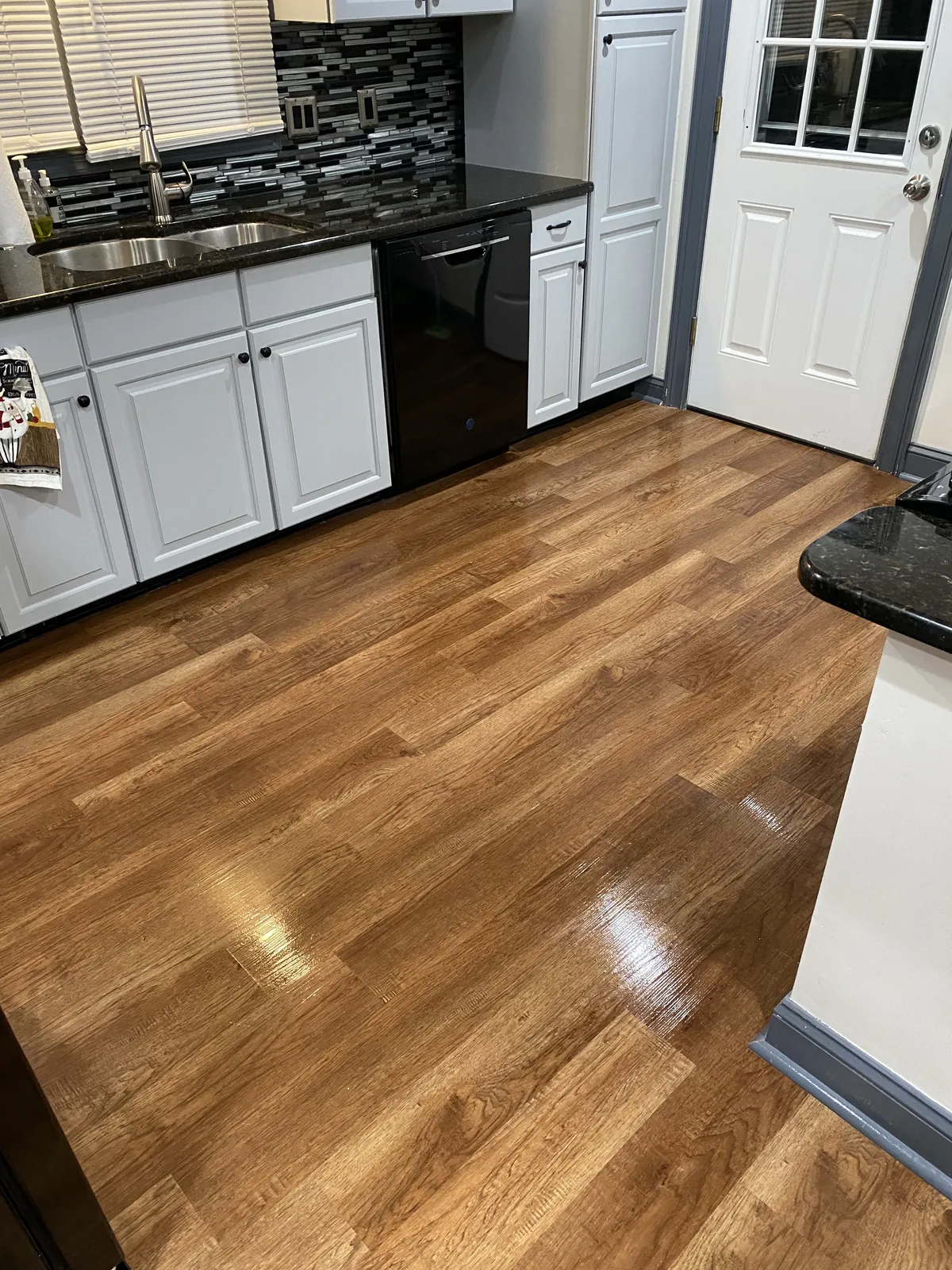 Kitchen with white cabinets, an island, and hardwood flooring