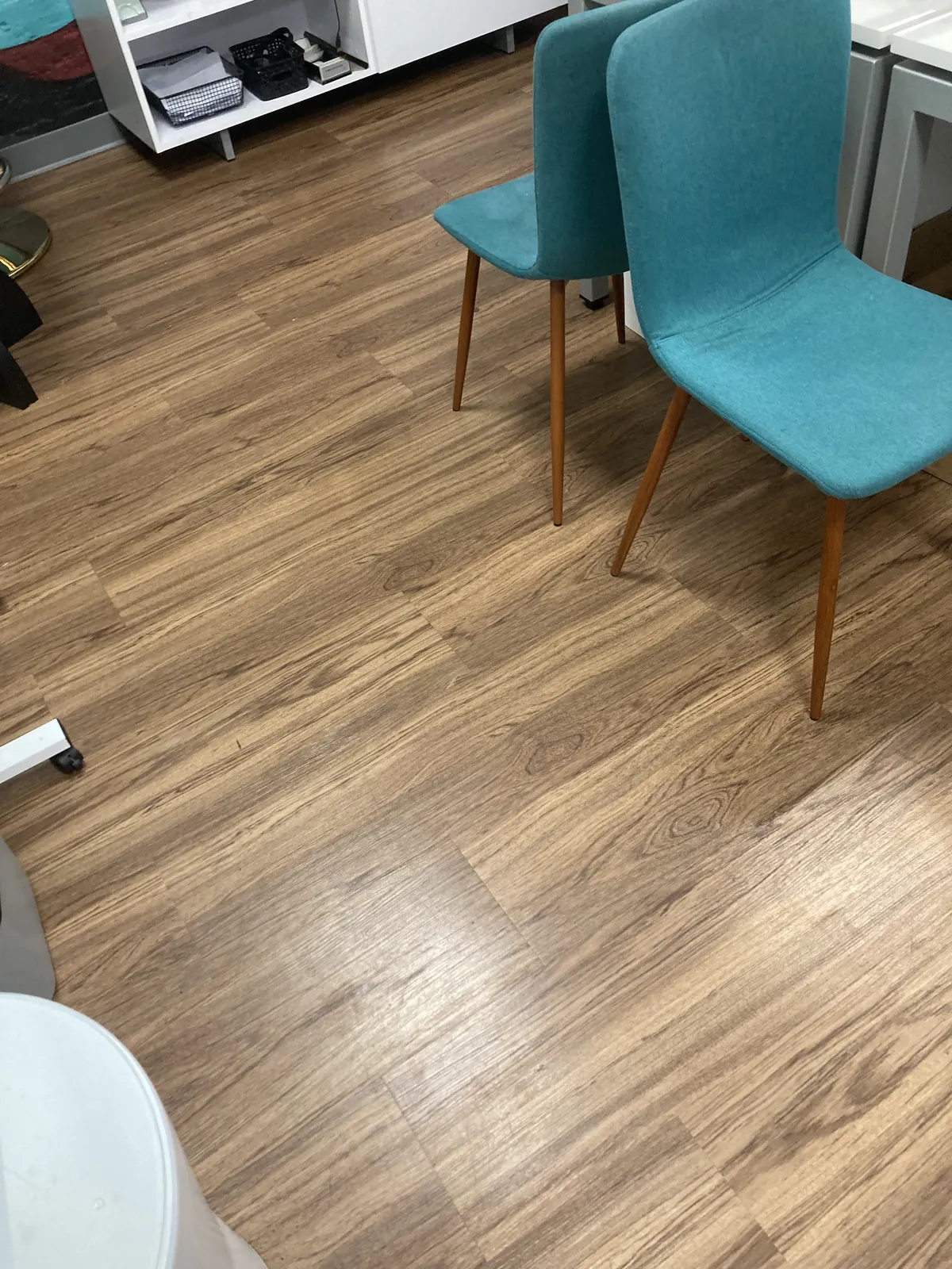 Office lounge with teal chairs and wood-look flooring