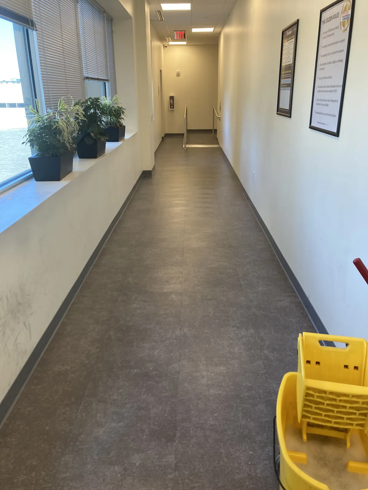 Commercial corridor with a yellow mop bucket on a tile floor