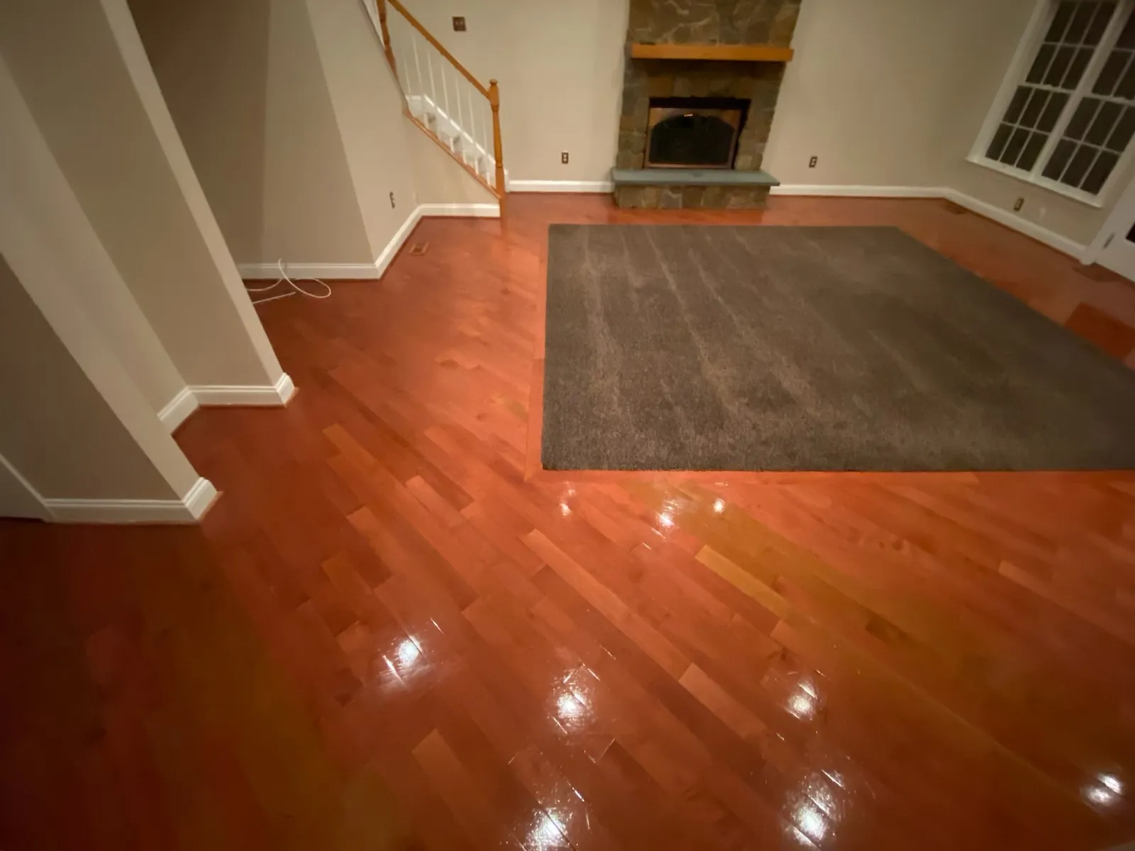 Empty room with polished hardwood flooring and a fireplace