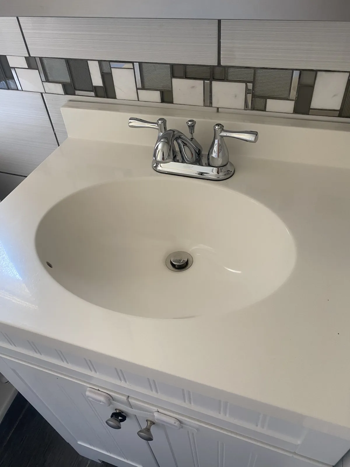 Bathroom vanity with a white sink, mirror, and toiletries