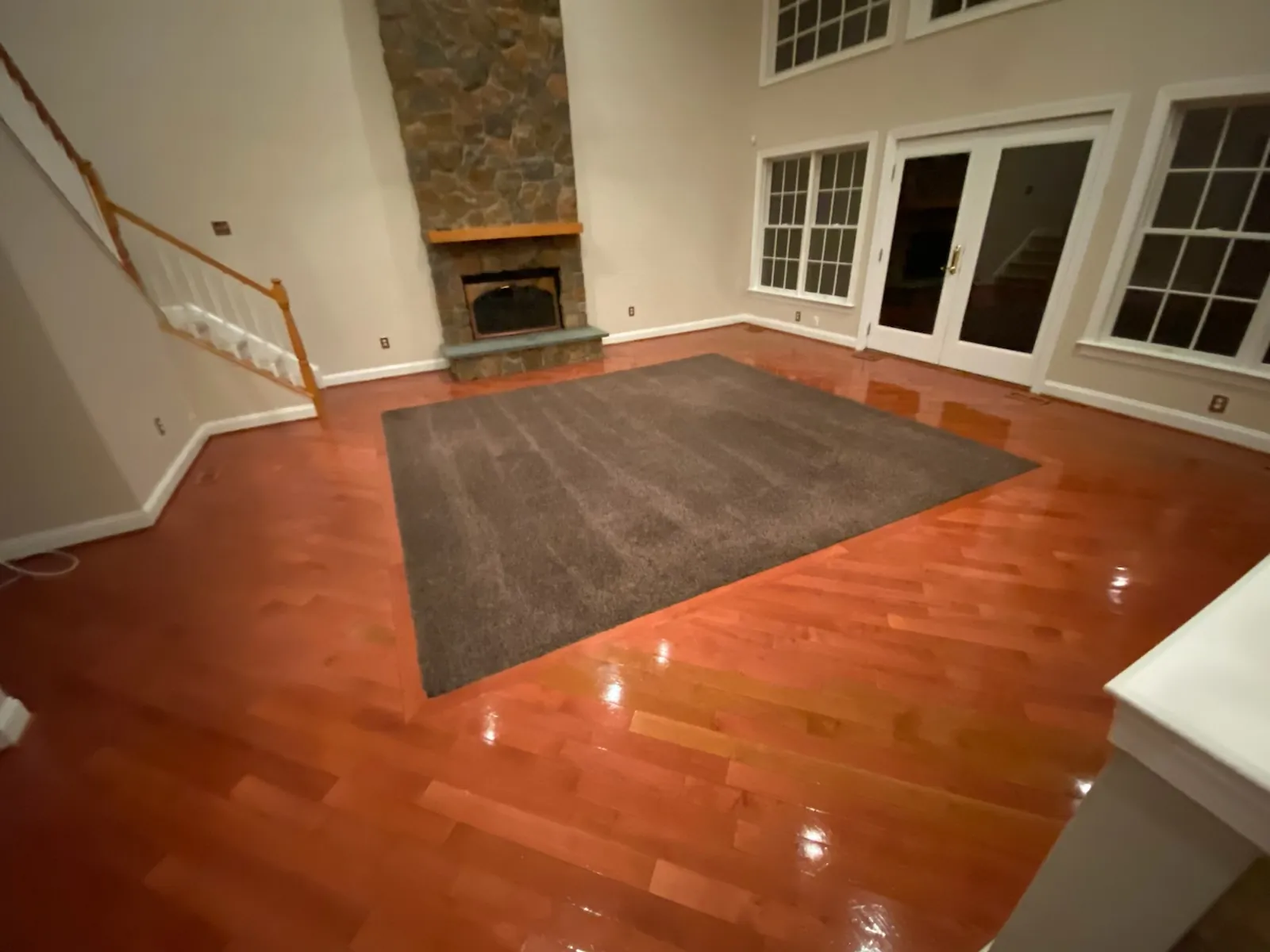 Sunlit living room with hardwood floors and a stone fireplace
