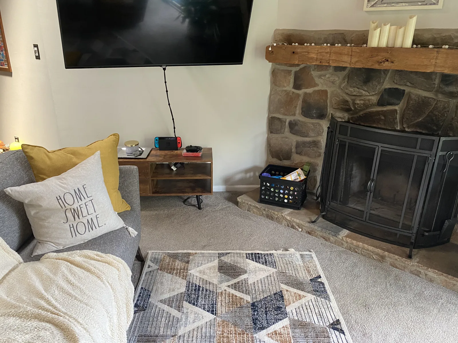 Living room with a sofa, area rug, and stone fireplace