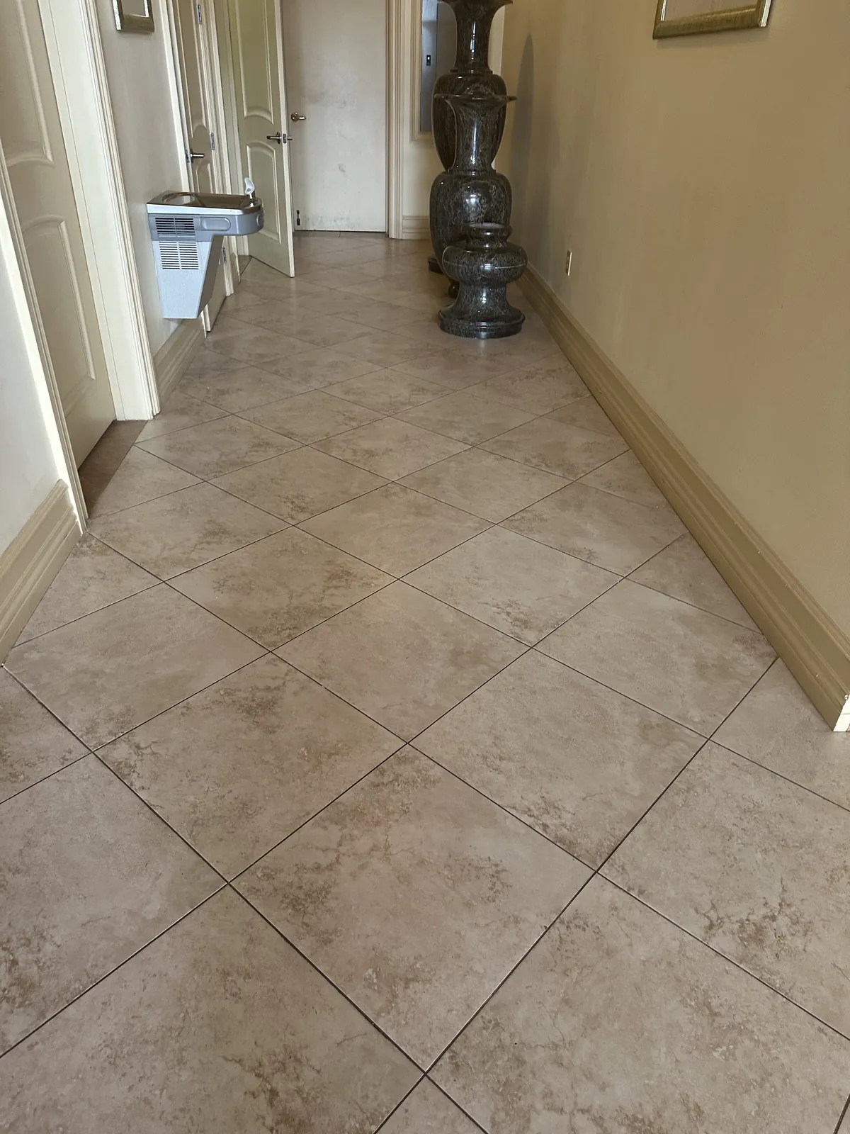 Tiled hallway with a drinking fountain and decorative pedestal
